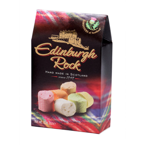 Traditional Edinburgh Rock confectionery from Gardiners of Scotland presented in a tartan-themed gift carton. The packaging features Scottish-inspired artwork, Edinburgh Castle imagery, and colorful pieces of handcrafted fruit-flavored rock candy, making it ideal as a souvenir or gift item.
